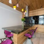 Stylish interior of contemporary kitchen with built in microwave and oven with stylish chairs around marble counter